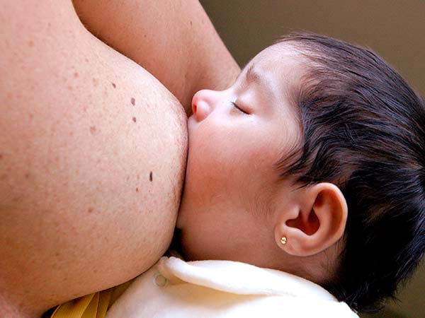 Fotografia de um bebê sendo amamentado no seio materno.