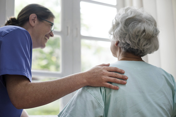 Foto de uma enfermeira tomando conta de uma senhora idosa.