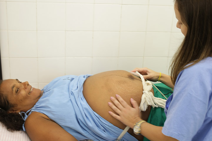 Fotografia de uma gestante sendo examinada por uma profissional de saúde.