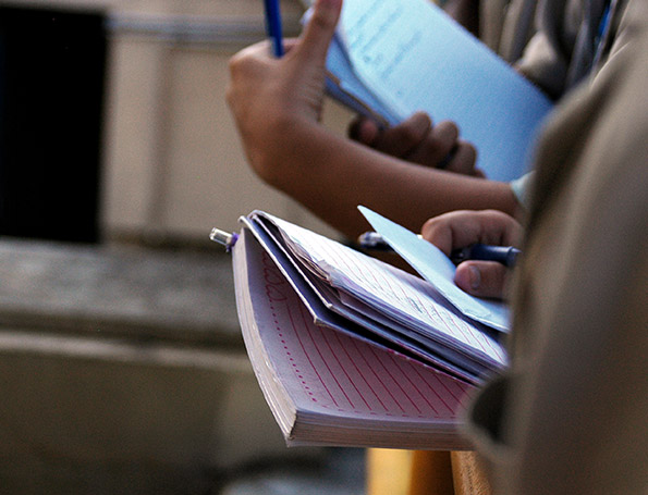 Fotografia de uma pessoa que segura uma caneta e um caderno com anotações.