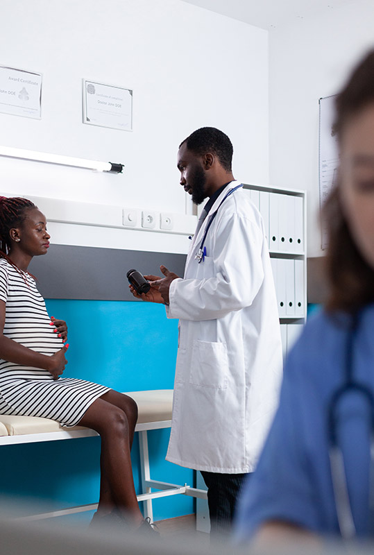 Fotografia de um profissional de saúde que aborda e conversa com uma gestante no consultório.