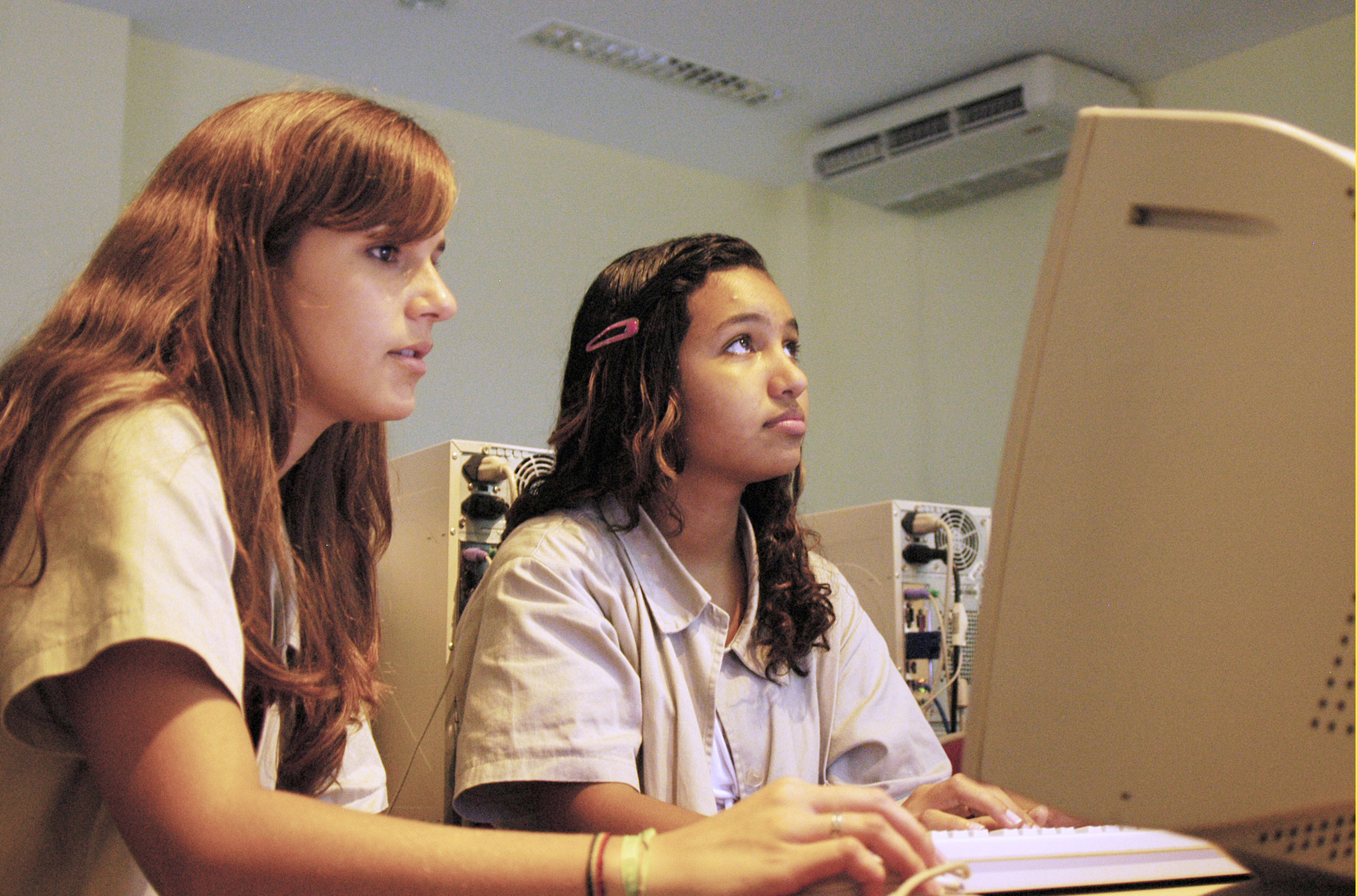 Fotografia de jovens garotas em frente ao computador.