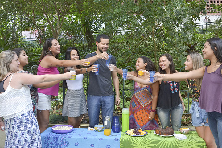 Fotografia de pessoas fazendo um brinde durante um piquenique em um ambiente arborizado.