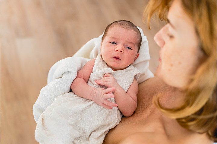 Fotografia em que uma mulher carrega um bebê recém-nascido no colo.