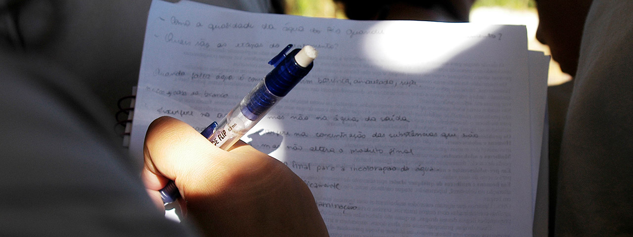 Fotografia de uma pessoa que segura uma caneta e um caderno com anotações.