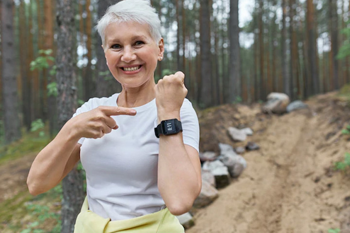 Fotografia de uma mulher com cabelos grisalhos que sorri e utiliza um relógio wearable.