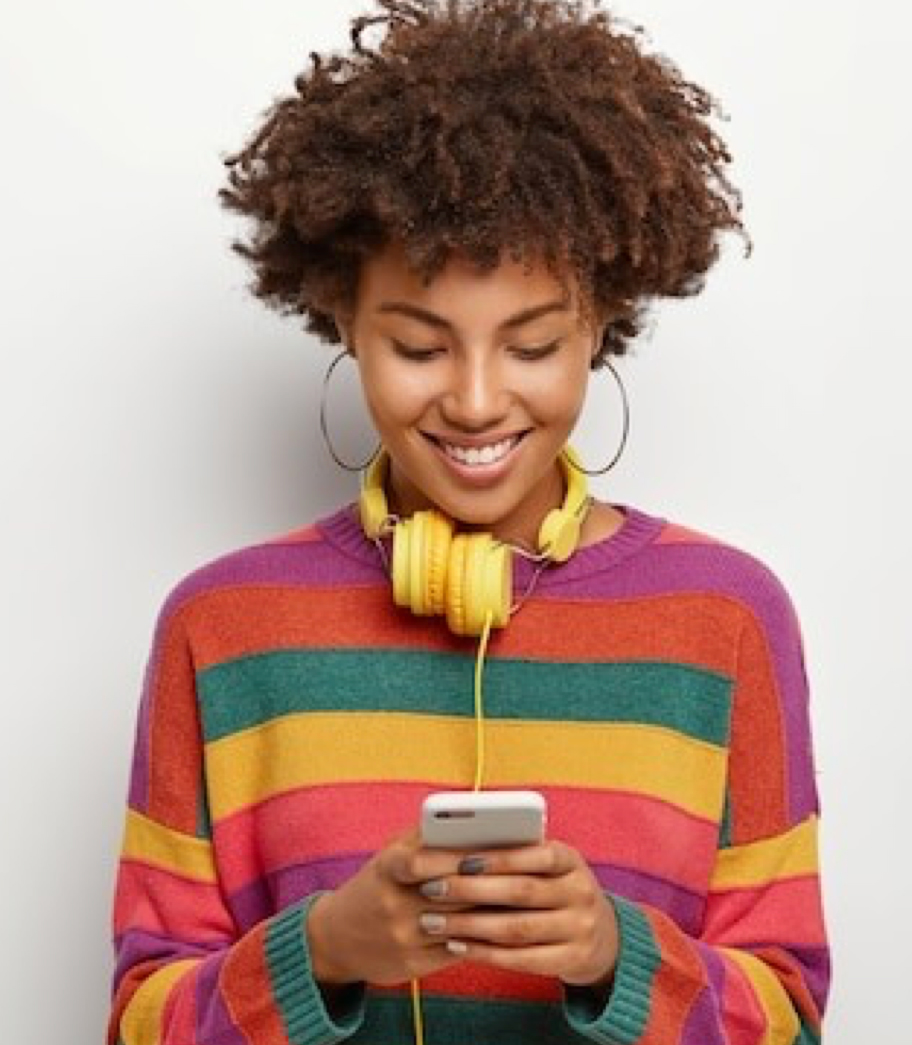 Fotografia de uma mulher que segura um smartphone nas mãos e sorri olhando para o equipamento.