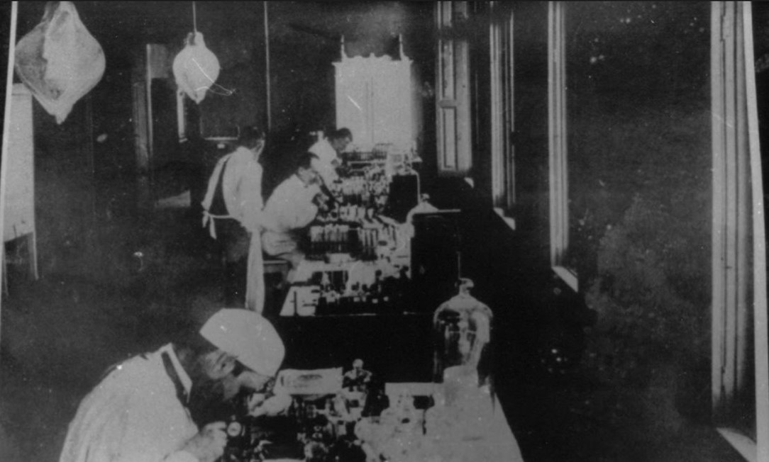 Adolfo Lutz ao microscópio, em primeiro plano, no laboratório do Instituto Bacteriológico de São Paulo.