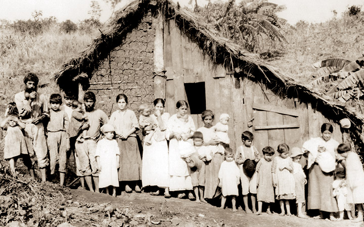 Grupo de sertanejos em frente a uma casa de pau a pique, em Lassance (MG).