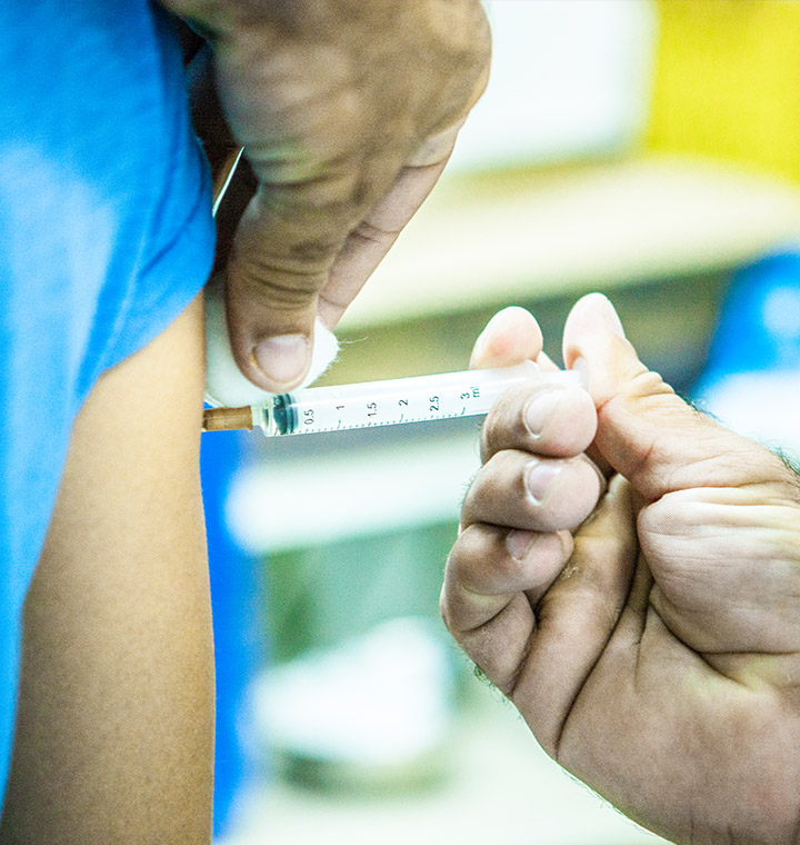 Médico aplicando vacina no braço de uma pessoa.